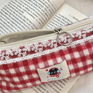 Detail of red checkered plush pencil case with lace trim and soft fleece texture