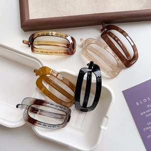 Detailed display of five color varieties of oval resin hair clips on a white tray