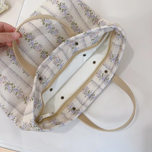 Top view of spacious floral canvas tote with metal zipper and purple stripe pattern