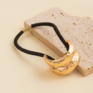 Detail of golden hammered metal buckle on black elastic hair tie for elegant ponytail style