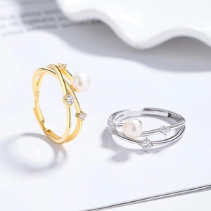 Macro shot of minimalist adjustable rings with pearls and sparkling cubic zirconia stones