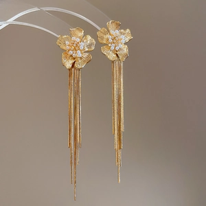 Macro shot of 18k gold plated flower earrings with pearls and long tassel details