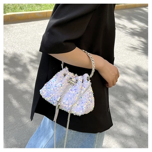 Outdoor shot of a white sequin drawstring bucket bag with iridescent effect and chain strap