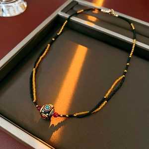 Dettaglio della collana vintage a doppio strato con perline dorate e ciondolo Dzi