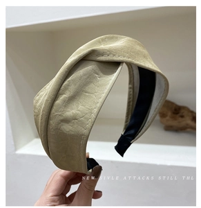 Detail of wide cream headband featuring a unique crinkled leather texture and black lining