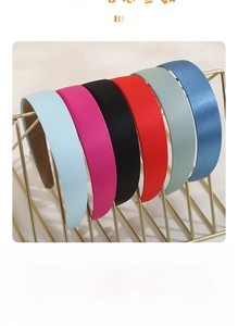 Close-up of six colorful satin headbands in macaron shades on a gold metal rack