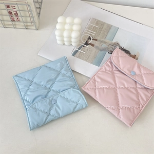 Detail of quilted glossy sanitary bag with heart button in light blue and pink colors