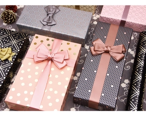 Detail of stacked gift boxes with geometric gold foil patterns and satin bow ribbons