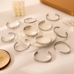 Minimalist silver stainless steel open bangles with sun and coin patterns on white background