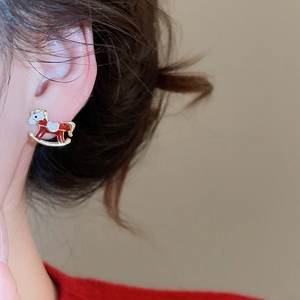 Gros plan d'une boucle d'oreille cheval à bascule rouge et blanc portée sur l'oreille