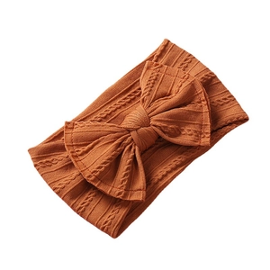 Soft burnt orange cable knit baby headband with a decorative large bow knot detail