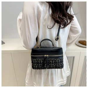Detailed view of the black gold tweed contrast box bag with dual zipper and top handle