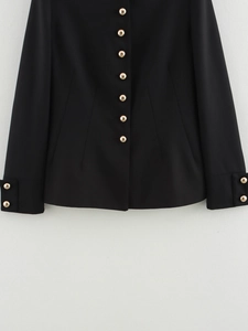 Close-up of black tailored jacket featuring embossed gold buttons and twill fabric detail