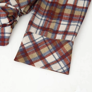 Close-up of red and brown plaid shirt cuff showing high-quality cotton fabric texture