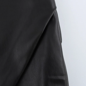 Detailed close-up showing the fine leather texture and side slit of the black PU skirt