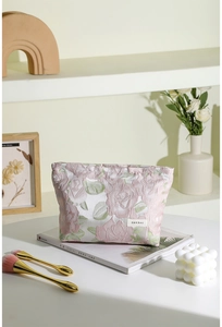 Gros plan du motif jacquard rose sur une trousse de maquillage avec étiquette tissée