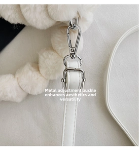 Detail of silver hardware adjustment buckle on white plush crossbody bag strap