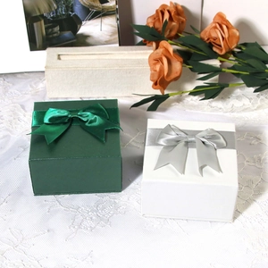 Elegant jewelry gift boxes in dark green and white with satin ribbon bows and texture