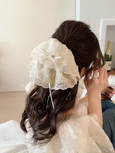 Close-up of white lace scrunchie with bow and pearl detailing on hair bun