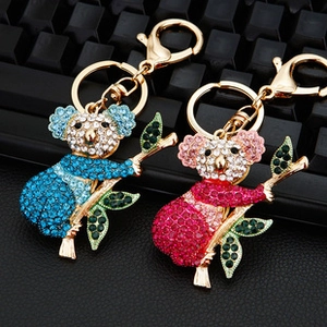 Detailed close-up of blue and pink rhinestone koala keychains on a black keyboard