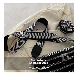 Detail der Nietensatteltasche mit breitem Chevron-Gurt und kleiner runder Geldbörse