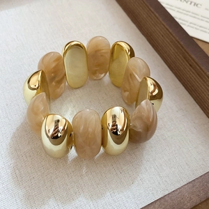 Close-up of gold metal and marble acrylic oval beads on a vintage elastic bracelet