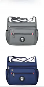 Detail of multi-pocket crossbody bag showing grey and blue nylon fabric with zippers