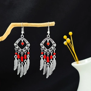Boucles d'oreilles bohèmes vintage avec perles rouges et plumes argentées sur fond noir