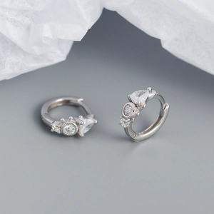Macro detail of silver drop earrings with sparkling zirconia stones on neutral background