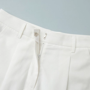 Detail of white trousers featuring metal hook-and-eye closure and high-quality zipper