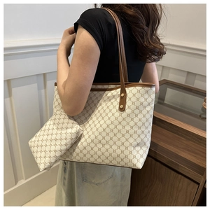 Detail view of a vintage beige patterned tote bag with matching zippered pouch on a model