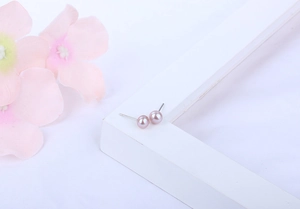 Macro shot of pink freshwater pearl earrings with 925 silver posts on a white frame