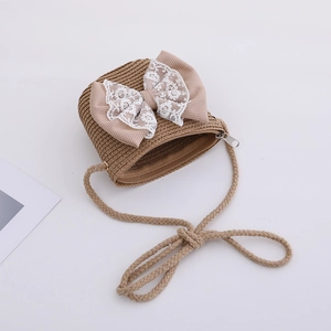 Close-up of khaki woven straw crossbody bag with lace bow and shoulder strap
