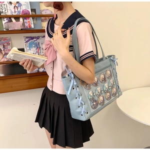 Detail view of light blue PU leather itabag featuring cross ribbon ties and transparent window