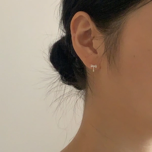 Side view of a 925 sterling silver bow earring with cubic zirconia on a female ear