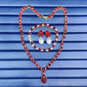 Detail view of heart-shaped ruby jewelry set with necklace and earrings on a blue tray
