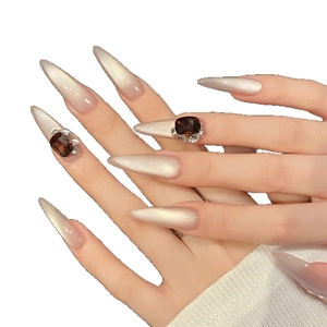 Long stiletto press-on nails with amber gems and sparkling crystal accents on pearly gradient