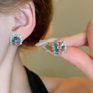 Macro shot of silver studs with aurora crystals and diamond halo worn on ear