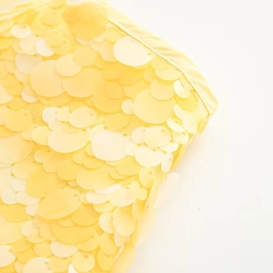 Detailed close-up of vibrant yellow sequins on stylish casual skirt fabric