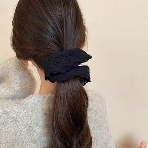 Detail view of black lace eyelet embroidered scrunchie on a low ponytail hairstyle