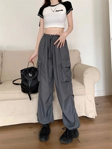 Detail of dark grey cargo pants with adjustable drawstring and large utility side pockets