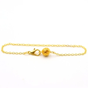 Detail view of a gold chain with hollow spherical charm and secure lobster clasp closure