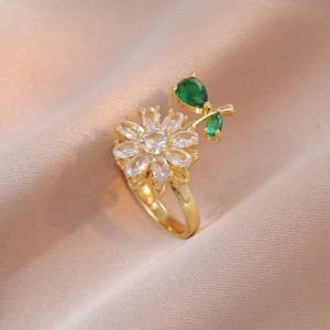 Macro shot of gold flower ring featuring clear petals and green pear-shaped zircon leaves