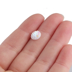 Macro shot of 8mm iridescent fish scale resin cabochon held in hand for DIY jewelry