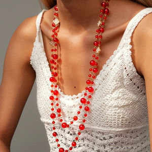 Detail of red crystal beaded long necklace with golden clover accents on a model