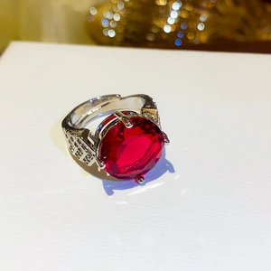 Macro shot of red zircon silver ring with side diamonds on warm golden bokeh background