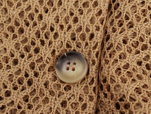 Detailed macro view of khaki crochet mesh fabric with a gradient resin button fastener