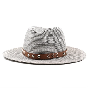 Detail of straw fedora hat with brown leather band and silver rivet accents