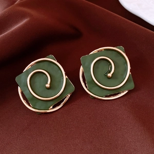 Macro shot of dark green square earrings with golden spiral pattern on velvet background