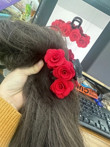 Detail of red flocked fabric roses on a black hair claw clip for elegant hairstyles